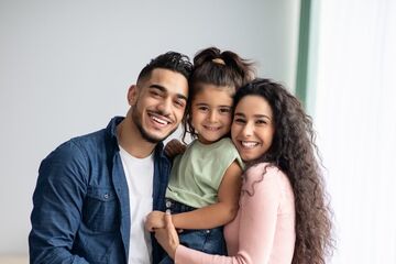 Man and woman holding child whilst smiling