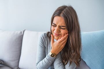 woman holding jaw in pain with signs of dental discomfort