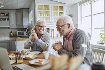 older couple sat smiling over breakfast