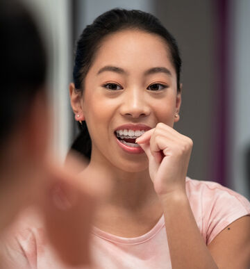 woman inserting invisalign into mouth